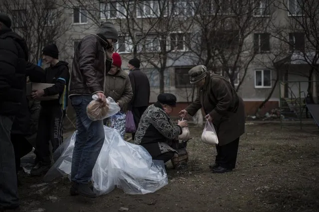 Local residents receive humanitarian aid after Saturday's shelling at Vostochniy district of Mariupol, Ukraine, Monday, January 26, 2015. (Photo by Evgeniy Maloletka/AP Photo)