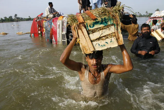 Locals rescue goods from a truck which overturned when it passed through a flooded road at Karamdad Qureshi village in Dera Ghazi Khan district of Punjab province, Pakistan August 21, 2010. (Photo by Reinhard Krause/Reuters)