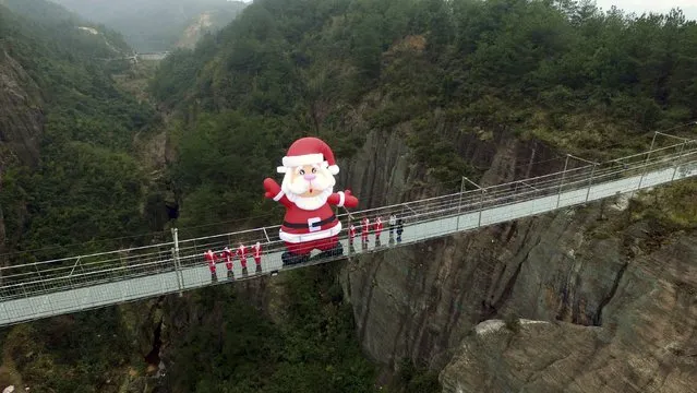A giant inflatable Santa Claus is set up on a glass bridge during a promotional event to celebrate the upcoming Christmas, at Shiniuzhai tourist resort in Yueyang, Hunan province, China, December 23, 2015. (Photo by Reuters/Stringer)