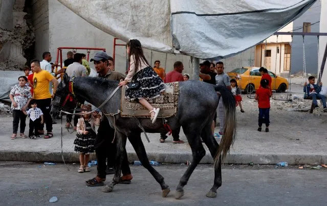 A child rides a horse as Iraqi people celebrate the first day of Eid al-Adha in the old city of Mosul, Iraq on June 28, 2023. (Photo by Khalid Al-Mousily/Reuters)