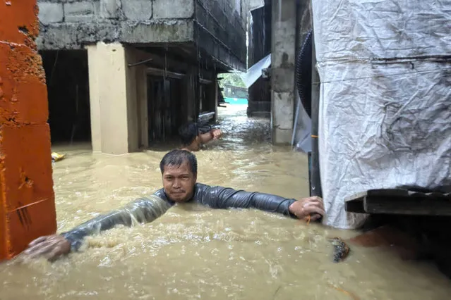 A man negotiates neck-deep floodwaters in his village caused by Typhoon Doksuri in Laoag city, Ilocos Norte province, northern Philippines, Wednesday, July 26, 2023. (Photo by Bernie Sipin Dela Cruz/AP Photo)