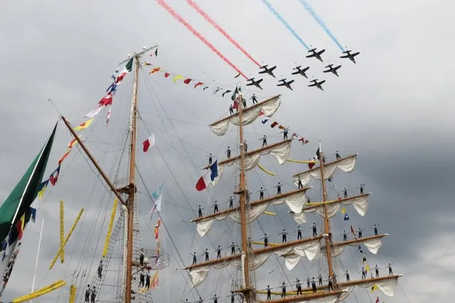 French aircraft patrol “Patrouille de France” planes fly over the Cuauhtemoc ship during the Grand Parade, as the ships sail from Rouen to the ocean through the Seine river, during the Armada of old vessels and tall ships in Rouen, on June 18, 2023. (Photo by Lou Benoist/AFP Photo)