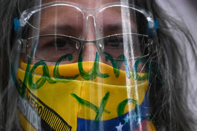 A nurse wears a face mask in the color of the Venezuelan flag and a face shield reading “Vaccine now” during a protest to demand all healthcare workers be vaccinated against COVID-19, at the Los Palos Grandes square, in Caracas on April 17, 2021. (Photo by Federico Parra/AFP Photo)