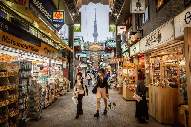 People wearing face masks walk through a shopping arcade in Asakusa area as Tokyo Skytree tower stands in the background on on April 29, 2021 in Tokyo, Japan. As Japan’s Golden Week holiday gets underway, the governors of Tokyo and its surrounding prefectures have urged residents to avoid travelling as the country grapples with a fourth wave of Covid-19 coronavirus. (Photo by Yuichi Yamazaki/Getty Images)