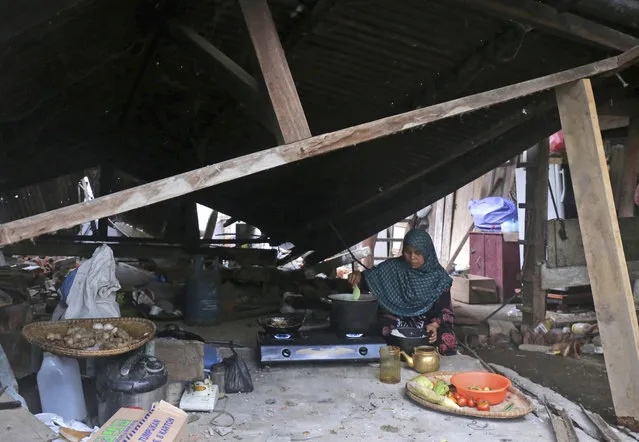 An earthquake survivor cooks breakfast at the ruin of her home in Pidie Jaya, Aceh province, Indonesia, Friday, December 9, 2016. Humanitarian organizations descended on Indonesia's Aceh province Thursday as the local disaster agency called for urgent food supplies and officials raced to assess the full extent of damage from an earthquake that killed a large number of people. (Photo by Heri Juanda/AP Photo)