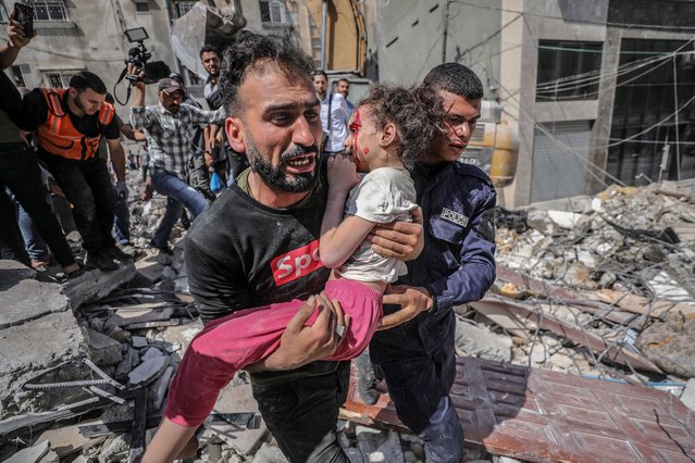 A Palestinian father evacuates his wounded daughter from the rubble of a destroyed house after an Israeli air strike in Gaza City, 16 May 2021. A total of 174 people have been killed in Israeli raids on Gaza, including 47 children and 29 women, the Palestinian Ministry of Health said on Sunday. In response violent confrontations between Israeli security forces and Palestinians in Jerusalem, various Palestinian militant factions in Gaza launched rocket attacks on Israel since 10 May, resulting in retaliatory strikes by Israel on Gaza. (Photo by Haitham Imad/EPA/EFE)