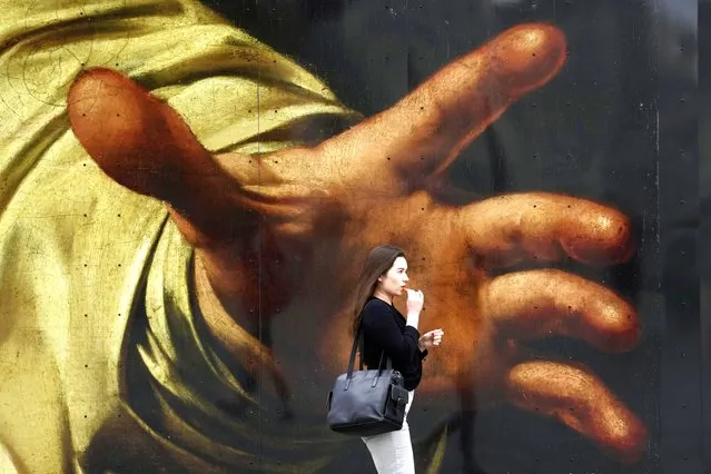 A woman walks past a poster featuring the painting of Caravaggio's “The Supper at Emmaus” outside the National Gallery, in London, Wednesday, September 13, 2023. (Photo by Kin Cheung/AP Photo)