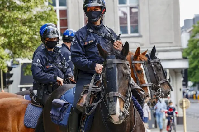 Mounted police officers patrol as people gather near EU headquarters during a so called “European Demonstration for Freedom and Democracy” protest against COVID-19 security measures taken by European governments, in Brussels, Saturday, May 29, 2021. (Photo by Olivier Matthys/AP Photo)