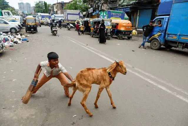 A boy pushes a goat after it came in the way of a street cricket match in Mumbai, India on September 21, 2023. (Photo by Francis Mascarenhas/Reuters)