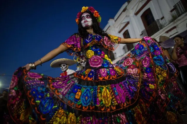 Performers dance during a Day of the Dead parade in Juchitan, Mexico, Wednesday, October 31, 2018, the town where a caravan of thousands of Central American migrants are resting for a day as they make their way to the U.S. border. (Photo by Rodrigo Abd/AP Photo)