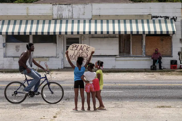 Dakeria Anderson, 9, protests with the help of her sisters D'liyah, 6, and D'anyriah, 8, across the street from the Triple S market where Alton Sterling wash shot and killed in Baton Rouge, LA, on July 11, 2016. The girls father, Dewayne Anderson said that he had been protesting since the beginning and the girls wanted to know what it was all about. The other side of the sign reads: no justice no peace. (Photo by Bonnie Jo Mount/The Washington Post)