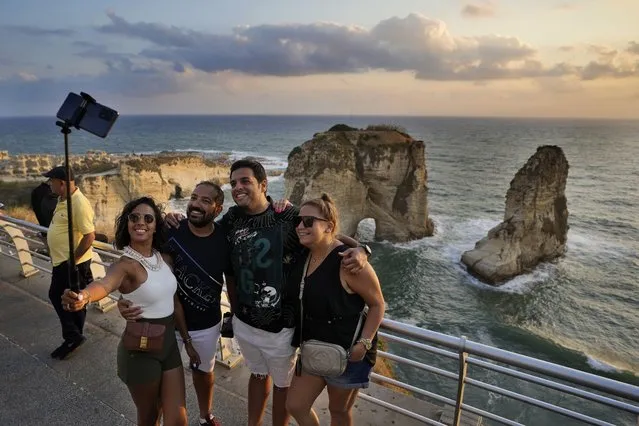 Egyptian tourists take a selfie in front the Rawcheh Sea Rock as the sun sets over the Mediterranean Sea in Beirut, Lebanon, Friday, July 2, 2021. (Photo by Hassan Ammar/AP Photo)
