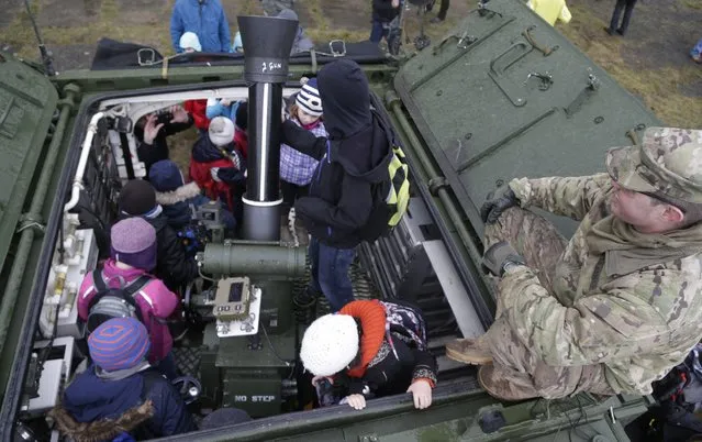 A US army soldier shows a stryker armored vehicle to children during a stop of their convoy in Prague, Czech Republic, Tuesday, March 31, 2015. (Photo by Petr David Josek/AP Photo)