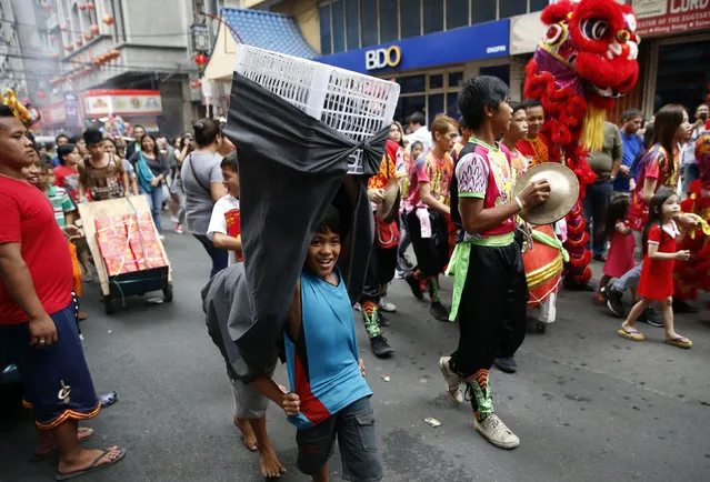 Boys follow lion dancers with an improvised costume on the eve of the Chinese New Year in Manila's Chinatown, Philippines February 7, 2016. (Photo by Erik De Castro/Reuters)