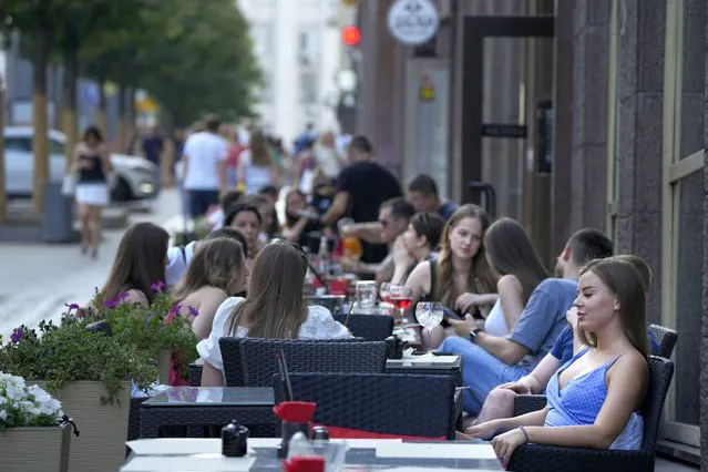 People relax after a hot day at an outdoor terrace of a restaurant in Moscow, Russia, Wednesday, July 14, 2021. The Russian capital recorded new record temperatures amid a heat wave this month with today's temperatures forecast 33 degrees Celsius (91,4 Fahrenheit). (Photo by Alexander Zemlianichenko/AP Photo)