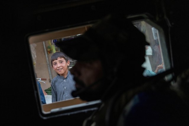 A boy watches as the convoy of Afghan Special Forces passes through a market during a combat mission against Taliban, in Kandahar province, Afghanistan, July 12, 2021. (Photo by Danish Siddiqui/Reuters)