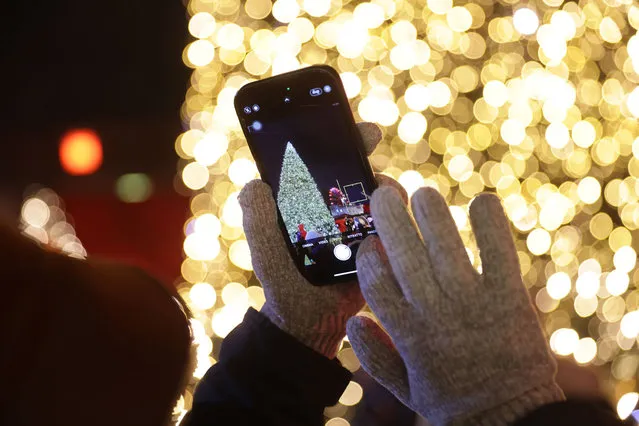 A visitor with a smartphone photographs an illuminated Christmas tree on the first day of the annual Christmas market at Red City Hall on November 27, 2023 in Berlin, Germany.  Christmas markets are opening across Germany this week. (Photo by Sean Gallup/Getty Images)