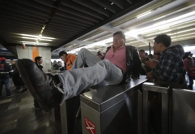 A man jumps over the turnstiles without paying to protest against a fare hike, at Cuatro Caminos subway station in Mexico City December 13, 2013. According to local media, Mexico City authorities raised the subway fare from 3 Pesos to 5 Pesos, an approximate increase of $0.15, starting on December 13, 2013. (Photo by Henry Romero/Reuters)
