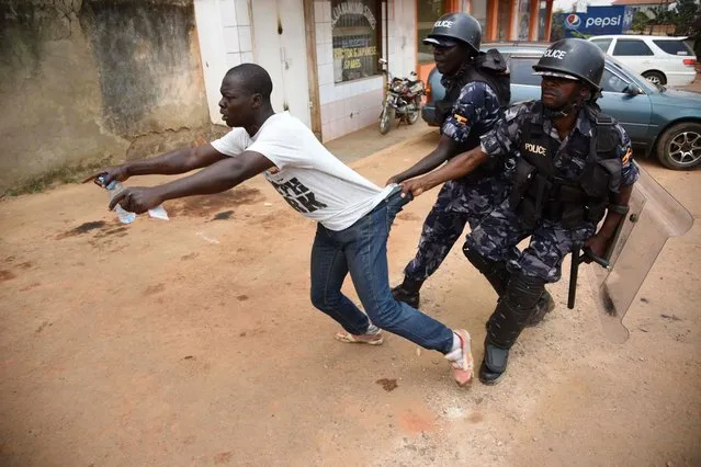 Ugandan policemen arrests a protester on February 19, 2016 in Kampala, as presidential and parliamentary votes were disrupted in the capital by the late arrival of ballot boxes and papers, angry demonstrations by frustrated voters and police using tear gas. Ugandan police stormed opposition party headquarters and arrested top presidential challenger Kizza Besigye on February 19, as early results showed veteran leader Yoweri Museveni enjoyed a solid lead in the country's chaotic elections. (Photo by Isaac Kasamani/AFP Photo)