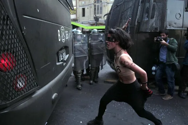 A woman strikes a police truck with her hand during a protest march in Santiago, Chile, Thursday, April 16, 2015. Thousands of students marched through the streets of Chile's capital to protest recent corruption scandals and to complain about delays in a promised education overhaul. While it was largely peaceful, violence broke out at the end when hooded protesters threw rocks and gasoline bombs at police. (Photo by Luis Hidalgo/AP Photo)