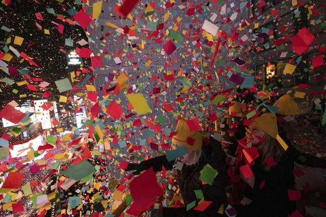Times Square Alliance volunteers throw confetti as the clock strikes midnight as seen from the New York Marriott Marquis during the New Year's Eve celebration in Times Square, Monday, January 1, 2024, in New York. (Photo by Yuki Iwamura/AP Photo)
