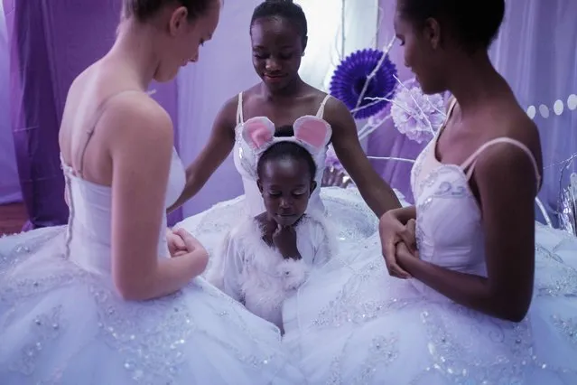 Members of Dance Centre Kenya (DCK) speak with the caricature the “sugar plum fairy” before the start of a production of the “Nutcracker”, a ballet primarily performed during the Christmas period as their fourth annual show, along with the Nairobi Philharmonic Orchestra playing the score by Pyotr Ilyich Tchaikovsky at the National theater in Nairobi, on December 2, 2018. DCK, founded by a few passionate families in early 2015, teach over 600 students at 3 studios in Nairobi, and provides lessons based on the Royal Academy of Dance Syllabus. Selected students in various schools and slums receive scholarships to promote developing their talents. (Photo by Yasuyoshi Chiba/AFP Photo)
