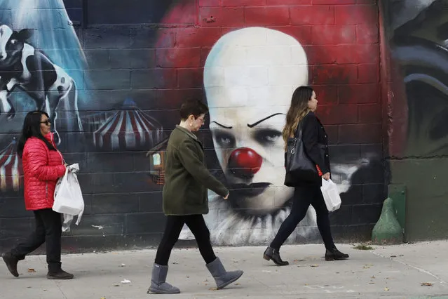 In this Wednesday, November 7, 2018, photo, people walk past a mural in Long Island City in the Queens borough of New York. Across the East River from midtown Manhattan, Long Island City is a longtime industrial and transportation hub that has become a fast-growing neighborhood of riverfront high-rises and redeveloped warehouses, with an enduring industrial foothold and burgeoning arts and tech scenes. (Photo by Mark Lennihan/AP Photo)