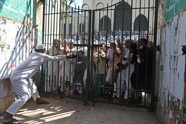 Protesters try to break a locked gate of the National Mosque during a demonstration after the Friday prayers in Dhaka on October 15, 2021, as protests began on October 13 after footage emerged of a Koran being placed on the knee of a figure of a Hindu god during celebrations for the Hindu festival of Durga Puja. (Photo by Munir Uz Zaman/AFP Photo)