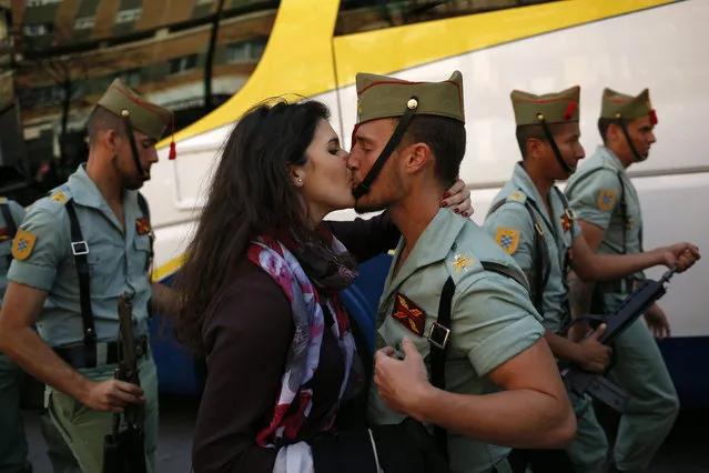 Spanish legionnaire Diego Ventura, 29, kisses his girlfriend, Sara Lara, 23, after taking part in a guard of honour ceremony in front of a statue of the Christ of Mena (not pictured) outside a church before he takes part in the Mena brotherhood procession in Malaga, southern Spain, March 24, 2016. (Photo by Jon Nazca/Reuters)