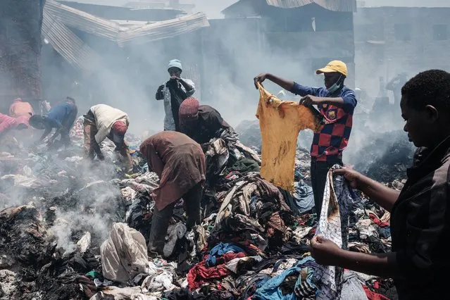 Traders scavenge clothes from debris burnt down by the fire in the early morning at Gikomba market, East Africa's largest second hand clothing market, in Nairobi, Kenya, on November 8, 2021. A court has ordered a part of the market to be evicted to build a health centre but many traders are against the decision, according to residents. (Photo by Yasuyoshi Chiba/AFP Photo)