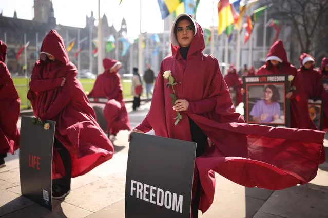 A protester dressed as a handmaid from The Handmaid's Tale holds a sign reading “Woman Life Freedom” prior to a march from Parliament Square to Iran's embassy to highlight repression of women in that country on March 8, 2024 in London, England. On March 8th International Women's Day celebrates the social, economic, cultural and political achievements of women globally and highlights the work still to be done to prevent endemic violence against women and inequality. (Photo by Dan Kitwood/Getty Images)