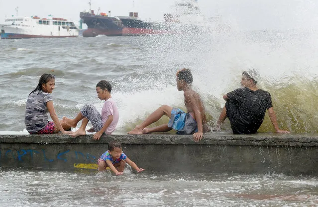 Residents along Manila Bay play in the waves created by nearby Typhoon Noul on May 10, 2015 as it approaches the northern Philippines. More than 2,000 people were fleeing their homes as Typhoon Noul approached the northern Philippines on May 10, triggering warnings of possible flash floods, landslides and tsunami-like storm surges. (Photo by Jay Directo/AFP Photo)