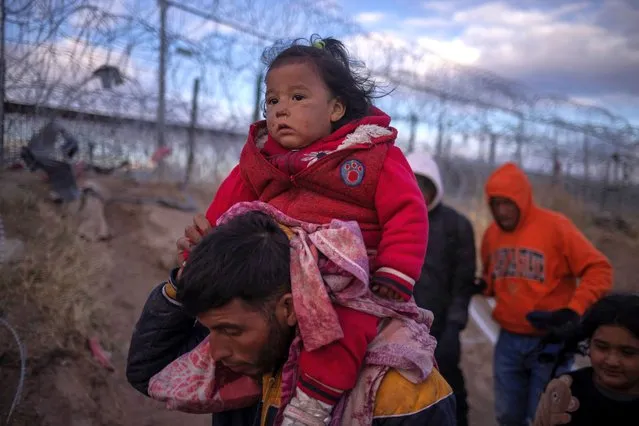 Briana, a one-year-old migrant girl from Peru, is carried by her father Jordan, as they search for an entry point into the United States past a razor wire-laden fence along the bank of the Rio Grande river in El Paso, Texas, U.S., March 26, 2024. (Photo by Adrees Latif/Reuters)