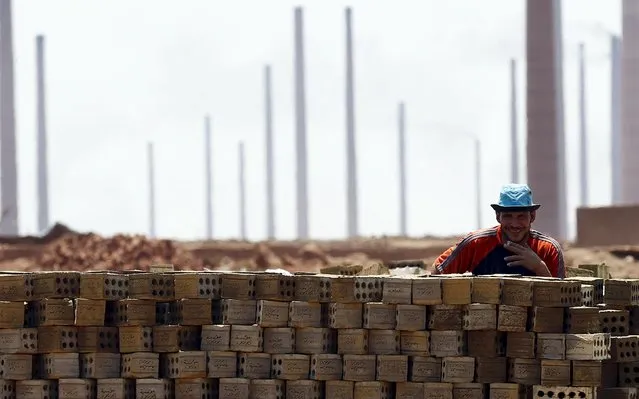 A labourer poses and smiles for a photo with bricks at a traditional brick factory in Arab Mesad district of Helwan, northeast of Cairo, May 14, 2015. (Photo by Amr Abdallah Dalsh/Reuters)