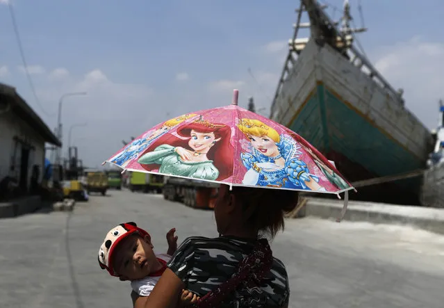 A woman carries her child while walking near wooden ships at Sunda Kelapa harbor in Jakarta, Indonesia, April 6, 2016. (Photo by Reuters/Beawiharta)