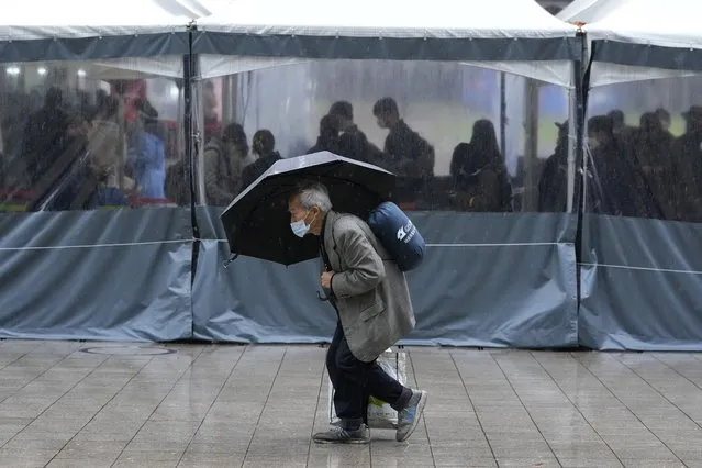 A man wearing a face mask passes by a makeshift COVID-19 testing site in Seoul, South Korea, Tuesday, November 30, 2021. (Photo by Ahn Young-joon/AP Photo)