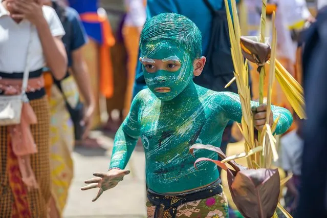 A child with his body and face painted prepares to attend the sacred Ngerebeg ritual at the Tegallalang village in Gianyar, Bali, Indonesia, 03 April 2024. The sacred Ngerebeg ritual takes place every six months and it is mainly aimed at driving all evil spirits out of the villages. During the ritual, the participants paint their bodies in various colors and patterns to join the procession across the village. (Photo by Made Nagi/EPA/EFE)