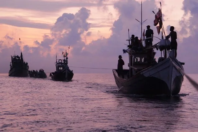 Acehnese fishermen are silhouetted by the rising sun as they rescue migrants who are stranded on their boat on the sea off East Aceh, Indonesia, Wednesday, May 20, 2015. Hundreds of migrants stranded at sea for months were rescued and taken to Indonesia, officials said Wednesday, the latest in a stream of Rohingya and Bangladeshi migrants to reach shore in a growing crisis confronting Southeast Asia. (Photo by S. Yulinnas/AP Photo)