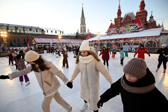 Women and girls take part in a figure skating master class at an outdoor ice skating rink in Red Square in downtown Moscow on December 10, 2021. (Photo by Natalia Kolesnikova/AFP Photo)