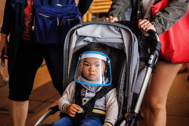 A baby wearing a face shield is seen on the forecourt of the Sydney Opera House on December 29, 2021 in Sydney, Australia. New South Wales has recorded 11,201 COVID-19 cases nearly doubling in the last 24 hours and reporting the highest daily caseload in any Australian state since the start of the pandemic. (Photo by Jenny Evans/Getty Images)