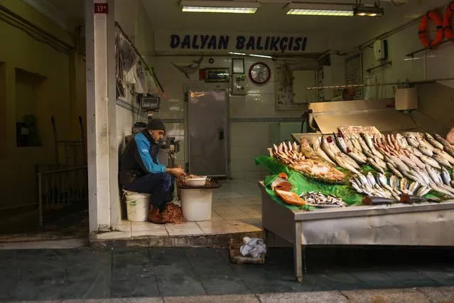 A fishmonger peels prawns as he waits for clients in a street market in Istanbul, Turkey, Monday, January 3, 2022. Turkey's yearly inflation climbed by the fastest pace in 19 years, jumping to 36.08% in December, official data showed on Monday. (Photo by Francisco Seco/AP Photo)