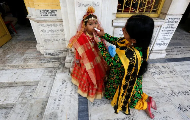 The mother of young girls dressed as Kumari applies lip gloss on her daughter before the start of the rituals to commemorate Navratri festival at Adyapith temple on the outskirts of Kolkata, India, April 15, 2016. (Photo by Rupak De Chowdhuri/Reuters)