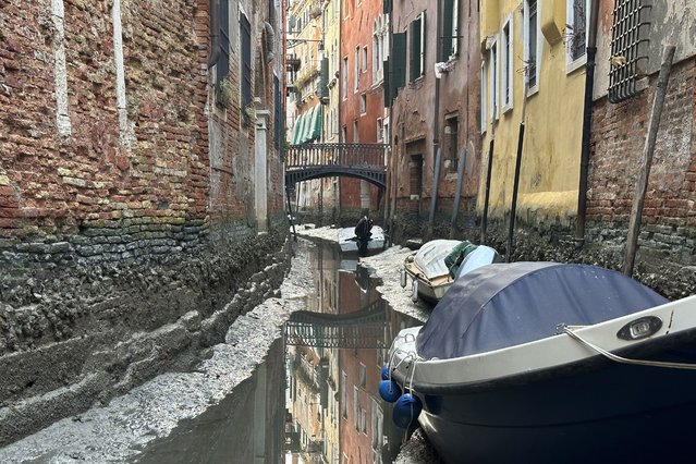 Boats are docked along a canal during a low tide in Venice, Italy, Monday, February 20, 2023. Some of Venice's secondary canals have practically dried up lately due a prolonged spell of low tides linked to a lingering high-pressure weather system. (Photo by Luigi Costantini/AP Photo)