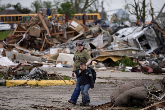 A woman and a child walk past damage after a tornado Tuesday, May 21, 2024, in Greenfield, Iowa. (Photo by Charlie Neibergall/AP Photo)
