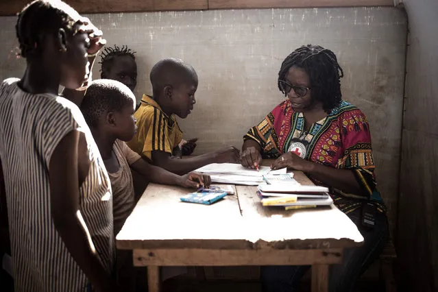 Children at the Lazare camp for internally displaced people (IDP) explain their drawings to the psychologist in Kaga Bandoro, Central African Republic on May 23, 2019. In the northern part of the country devastated by the crisis, the International Red Cross has set up a workshop to detect and treat Post Traumatic Stress Disorder through drawing. (Photo by Florent Vergnes/AFP Photo)