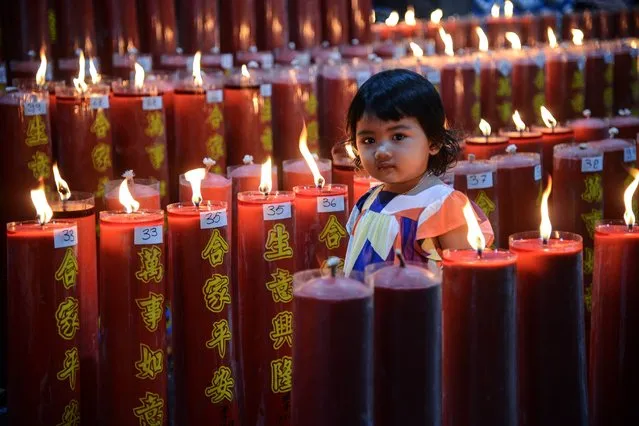 A girl is seen among candles during the Lunar New Year eve, the Year of the Tiger at a temple in Bogor, West Java, Indonesia on January 31, 2022. (Photo by Adriana Adie/NurPhoto via Getty Images)