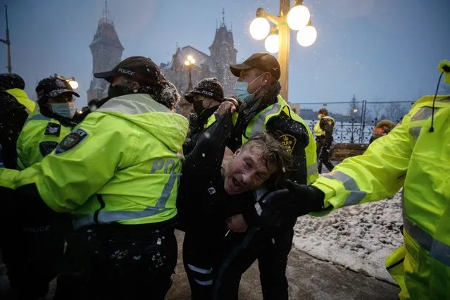 A man is arrested by police as protesters and supporters gather as a protest against COVID-19 measures that has grown into a broader anti-government protest continues to occupy downtown Ottawa, Ontario, on Thursday, February 17, 2022. (Photo by Cole Burston/The Canadian Press via AP Photo)
