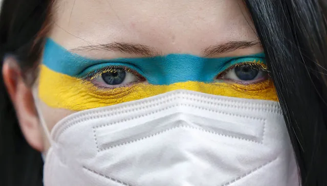 A woman wears make up in the colors of the Ukrainian flag protesting against Russian invasion of Ukraine in front of Brandenburg gate on February 24, 2022 in Berlin, Germany. Russia began a large-scale attack on Ukraine, with explosions reported in multiple cities and far outside the restive eastern regions held by Russian-backed rebels.(Photo by Hannibal Hanschke/Getty Images)