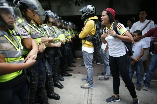 A woman yells at security forces blocking one of the routes for a silent protest in homage to the at least 20 people killed in unrest generated after the nation's Supreme Court stripped congress of its last powers, a decision it later reversed, at the start of a march to the Venezuelan Episcopal Conference in Caracas, Venezuela, Saturday, April 22, 2017. (Photo by Ariana Cubillos/AP Photo)