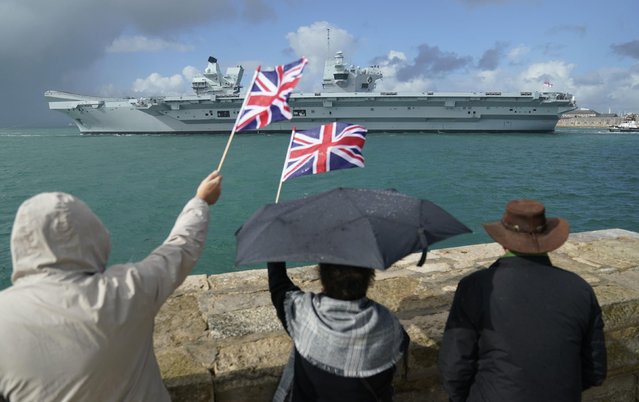 People wave from the shore as the Royal Navy aircraft carrier and flagship HMS Queen Elizabeth leaves Portsmouth Harbour for the United States, ahead of an autumn on operations and exercises in European waters on Wednesday, September 7, 2022. (Photo by Andrew Matthews/PA Images via Getty Images)